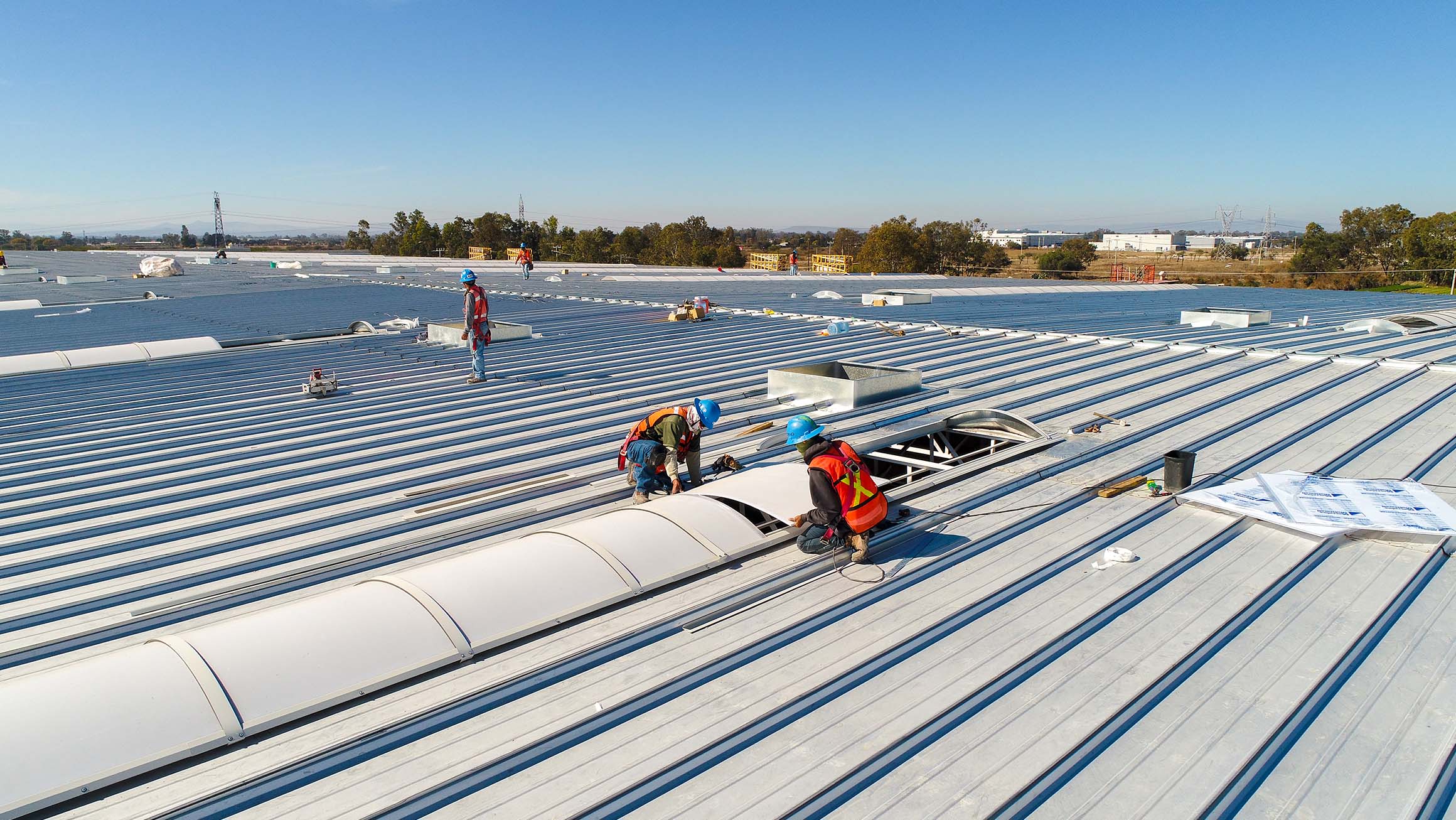 Construction workers installing roofing on an industrial park