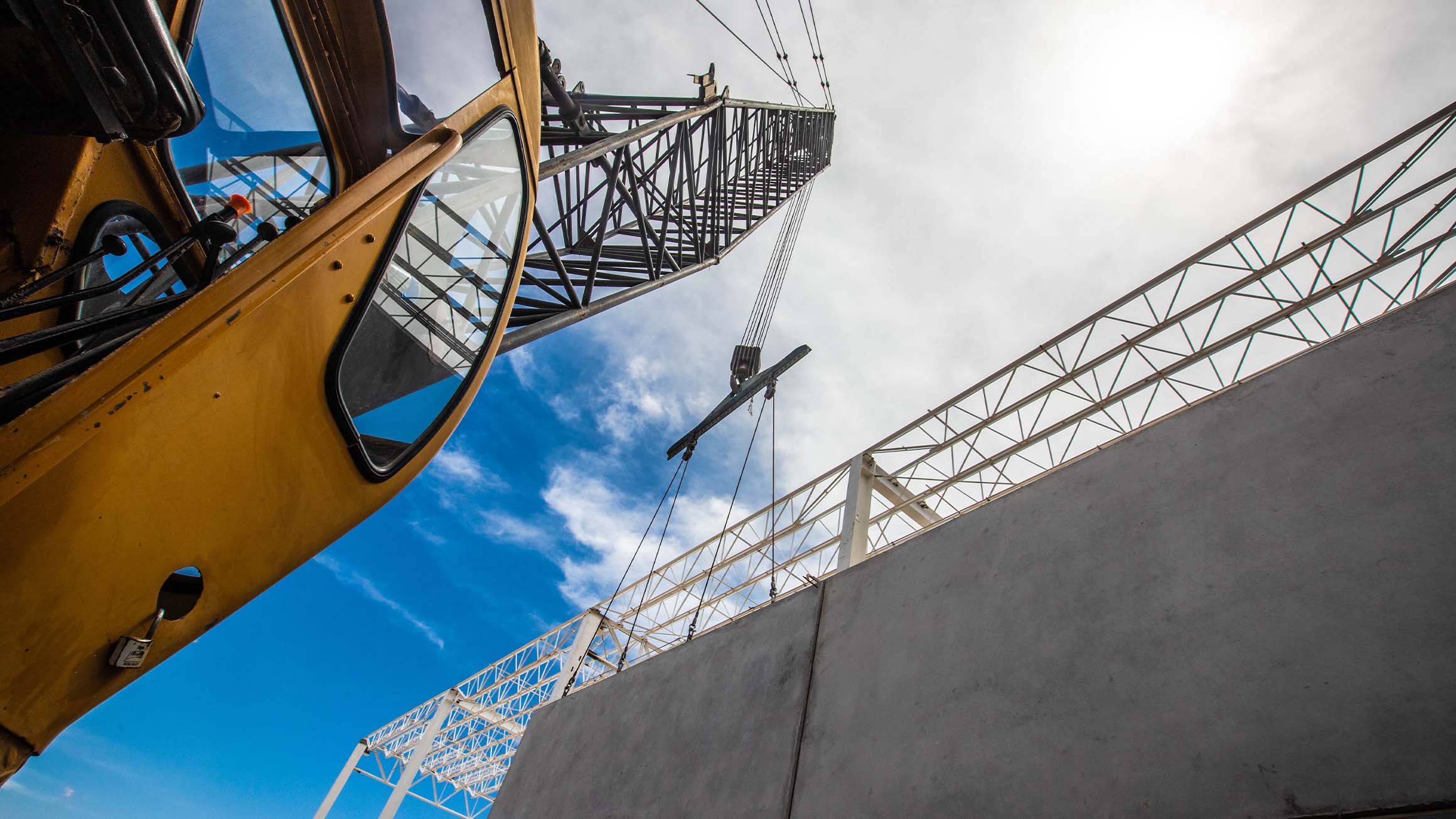 Photograph of a construction crane lifting concrete slabs on an industrial building construction site
