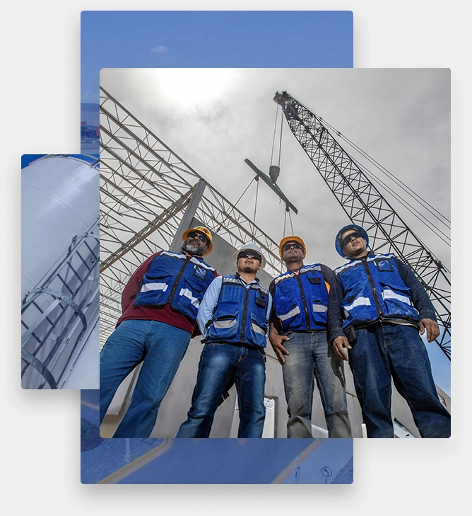 A group of construction workers posing in front of a crane in an industrial building construction site while wearing blue safety gear